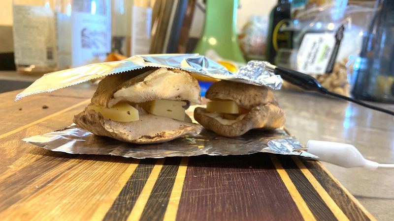 foil wrapped around two stacks of mushrooms and cheese. 