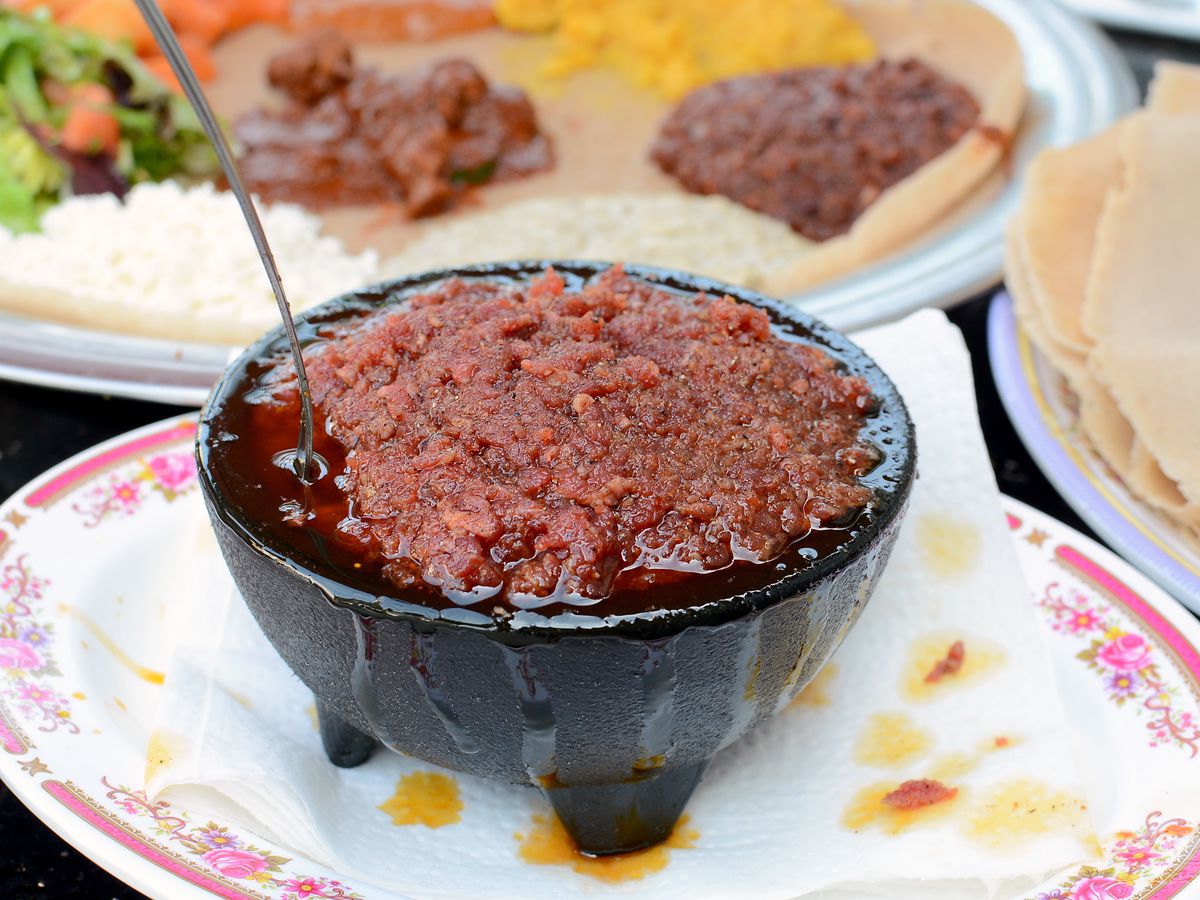 A bowl of Ethiopian kitfo / raw beef with a spoon on the side.