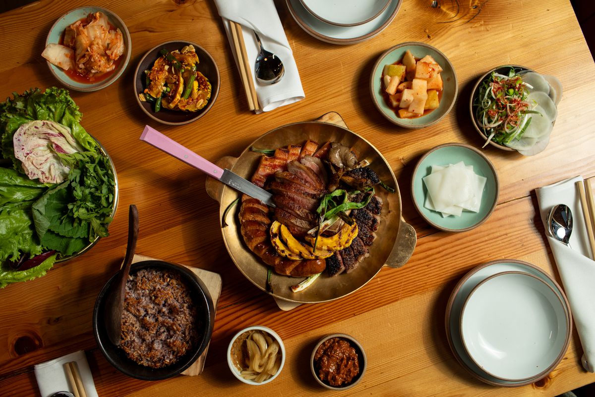 A platter of wood-fired Korean barbecue, surrounded by ssam components and purple rice, at Jeju.