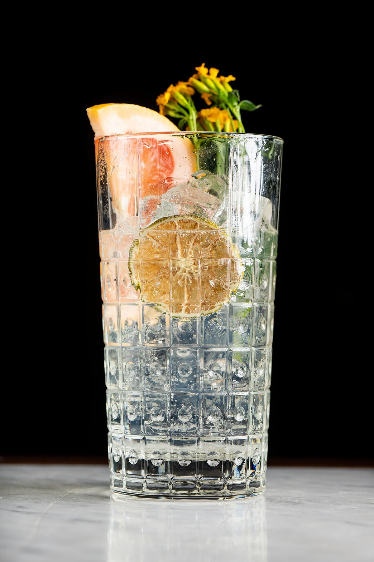 A tall clear cocktail glass with a slice of grapefruit and garnish.