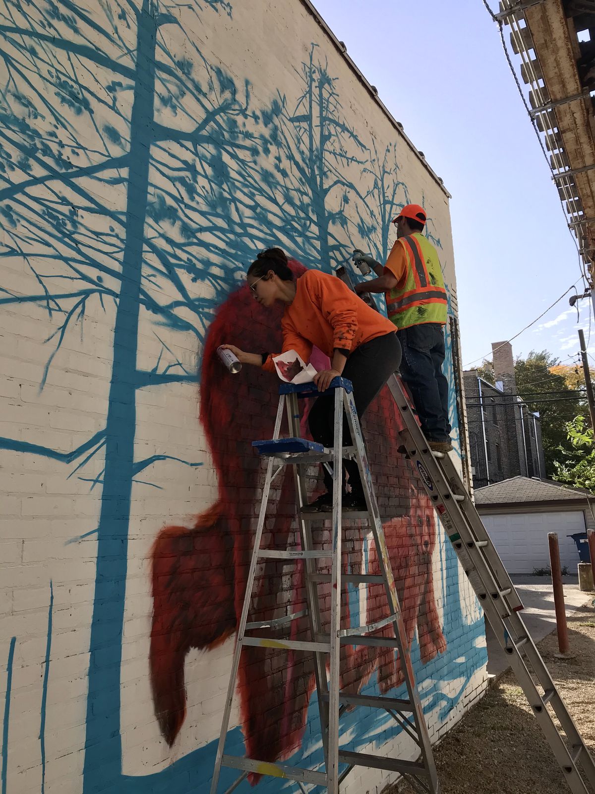 Felix Maldonado Jr. and his assistant Lisa Jones work to paint one of the bears in the mural.