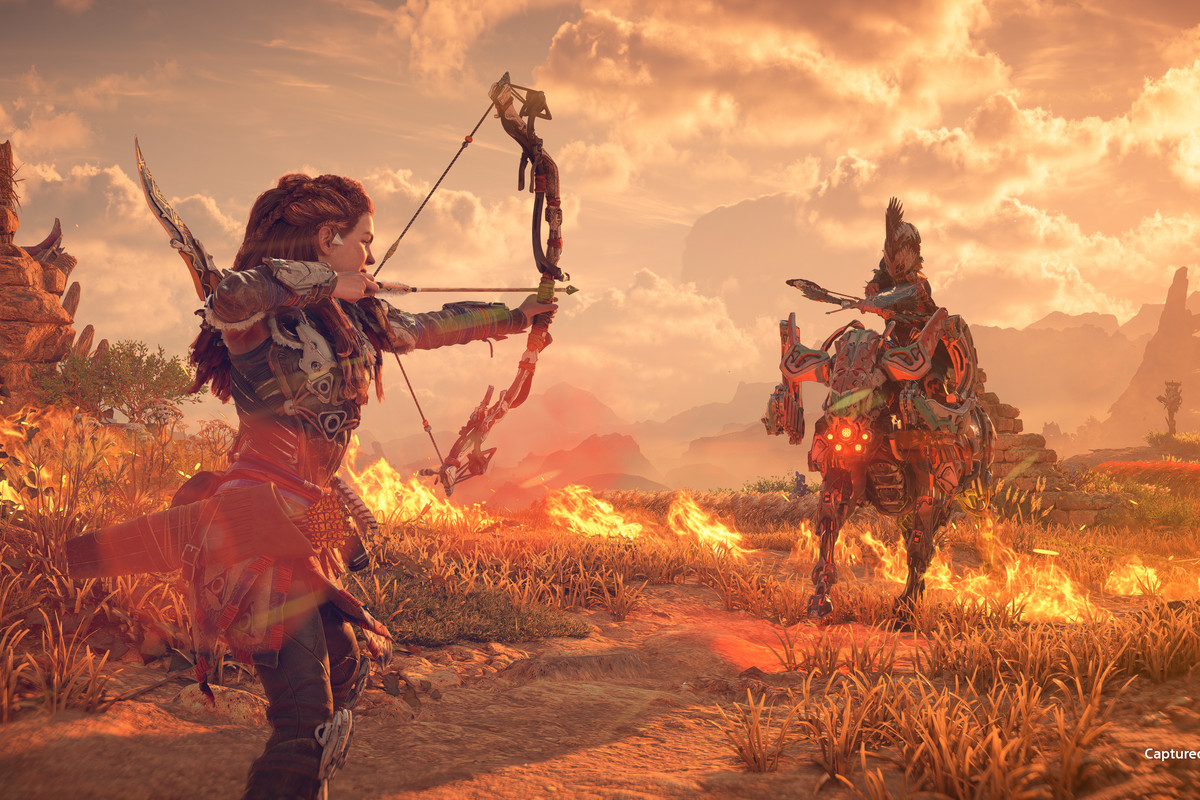 Aloy with her bow and arrow pulled back, aiming at a Tenakth warrior riding a Charger, in Horizon Forbidden West