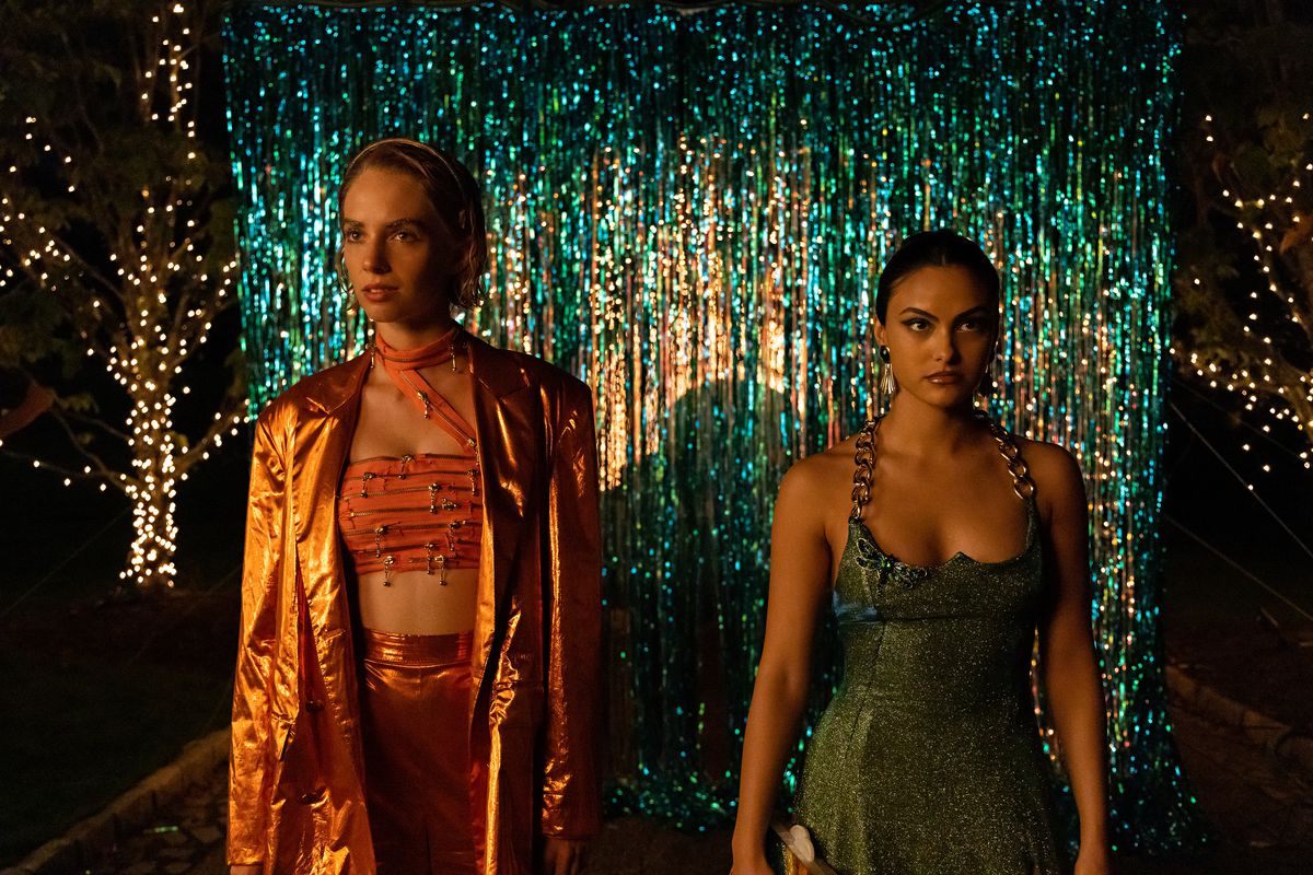Camila Mendes and Maya Hawke at Do Revenge wearing elegant outfits in front of a sparkling backdrop.
