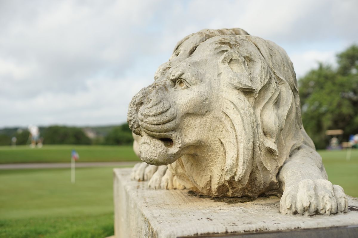 Lion statue with golf course in background