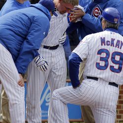 Chicago Cubs' Steve Clevenger, center, is assisted from the field by the training staff after he was injured during the ninth inning of a baseball game against the San Francisco Giants in Chicago, Saturday, April 13, 2013. The Giants won 3-2. 