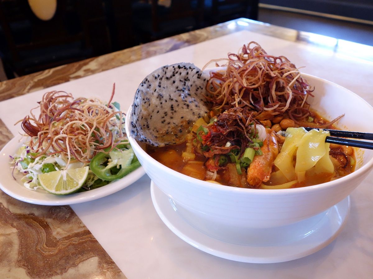 A bowl of mi quang, with turmeric noodles, pork spare ribs, prawns, and quail eggs.