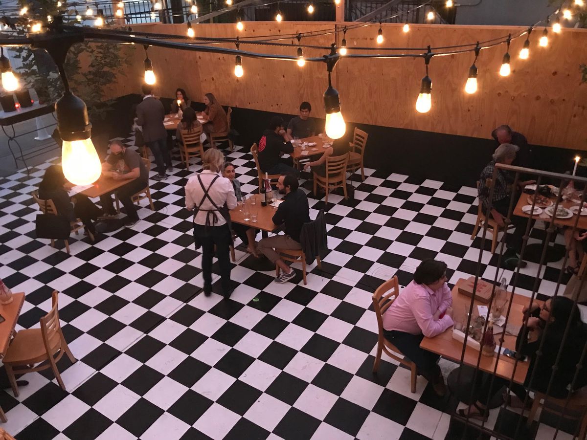 An ad hoc outdoor dining setup with tiled floor and string lights at Mozza in Hollywood, California.
