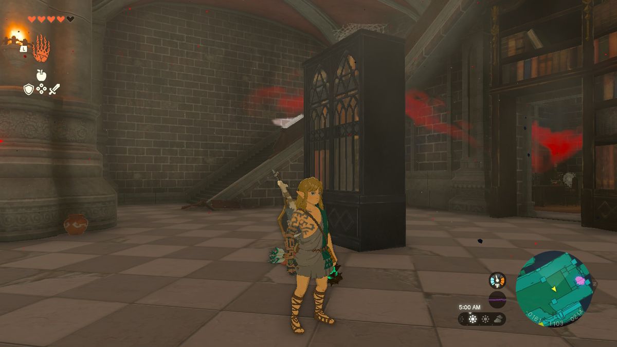 Link stands next to a bookcase near stairs in Hyrule Castle in Zelda Tears of the Kingdom.