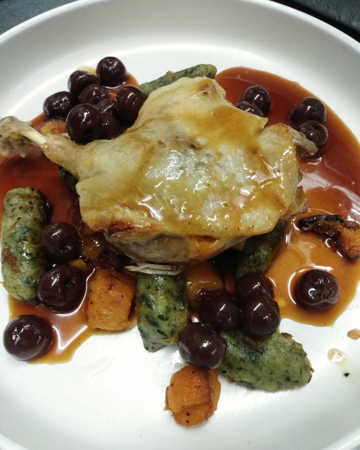Duck leg confit with brandied cherry sauce and homemade spinach-goat cheese gnocchi.