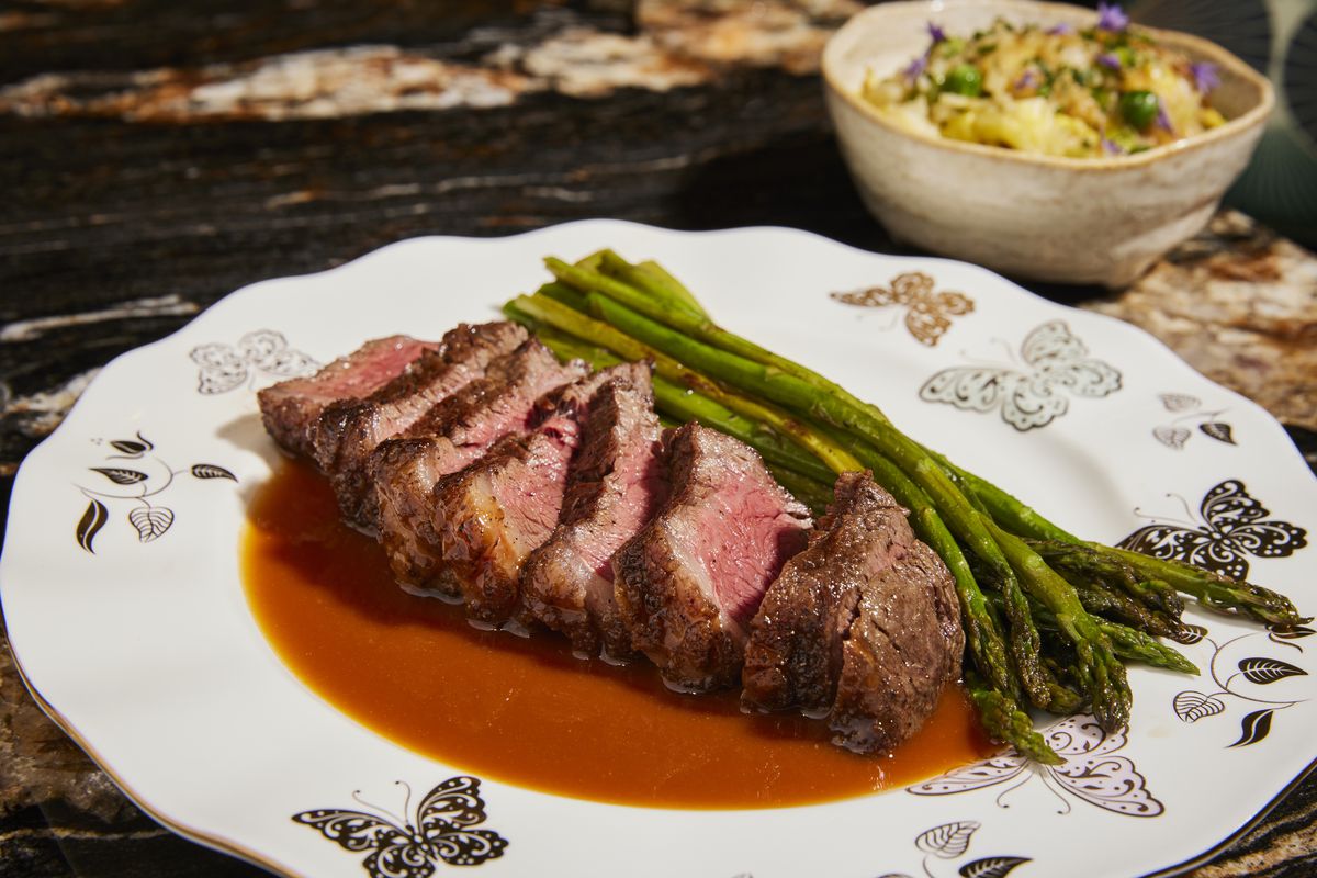 Maison Kasai’s Snake River farms American wagyu culotte with sauce Americaine on a decorated plate with asparagus.