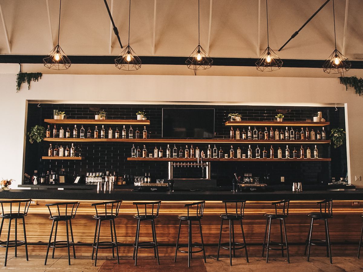 A classic bar with a liquor shelf and seats along it.