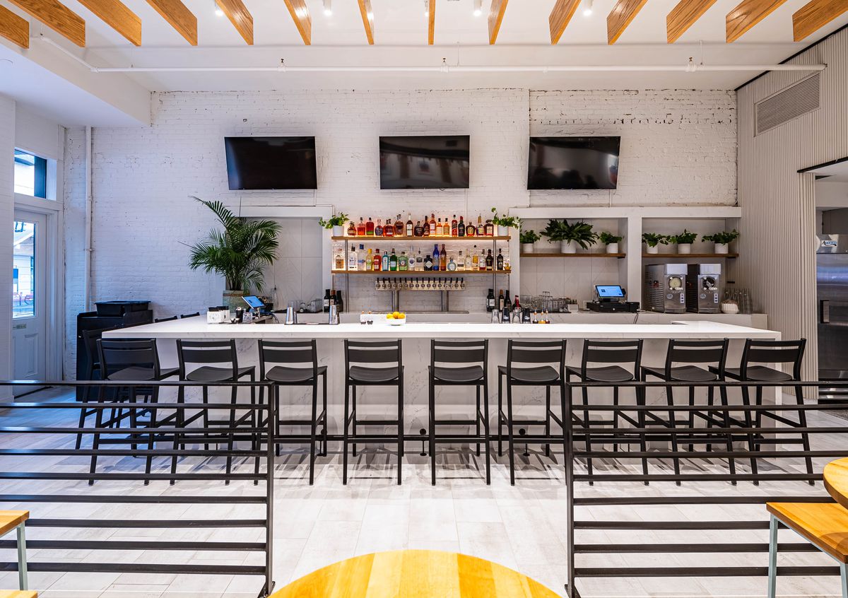 A white bar lined with black bar stools