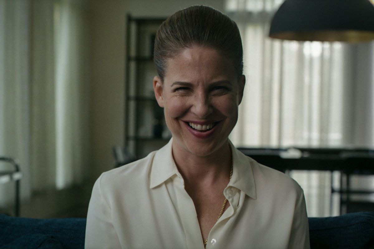 Robin Weigert as the therapist sitting in her office with a huge evil grin in Smile