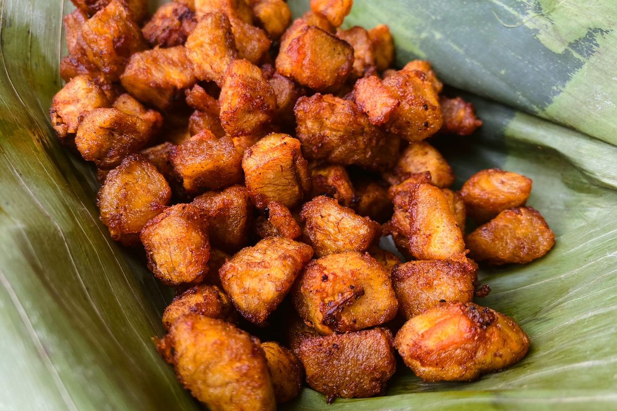 Fried brown chunks of plantains piled into a green banana leaf