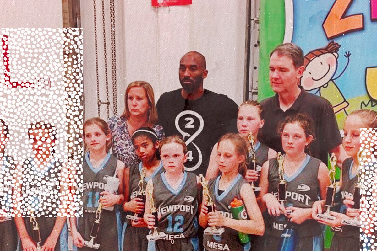Kobe Bryant stands in the middle of members of his youth basketball team, who are holding trophies.