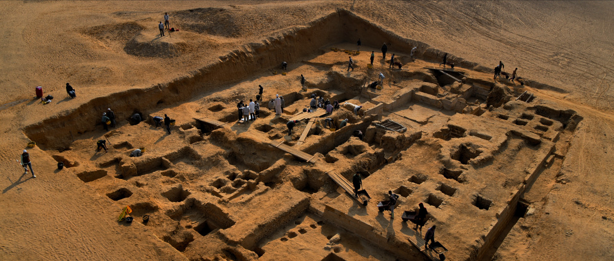 A wideshot of a set of ruins in the ground, with people doing work on them