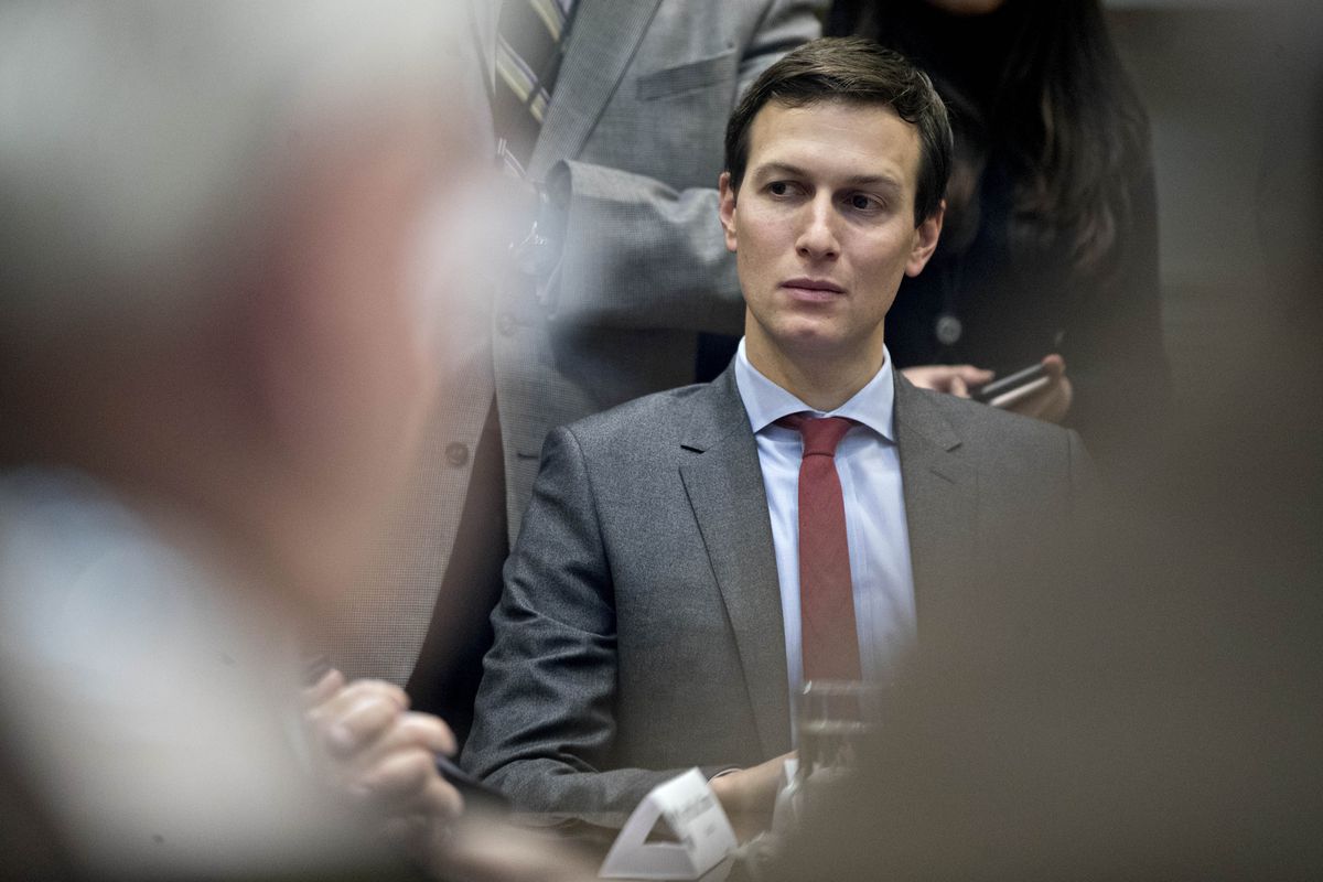 Jared Kushner wears a suit and red tie and sits at a conference room table.