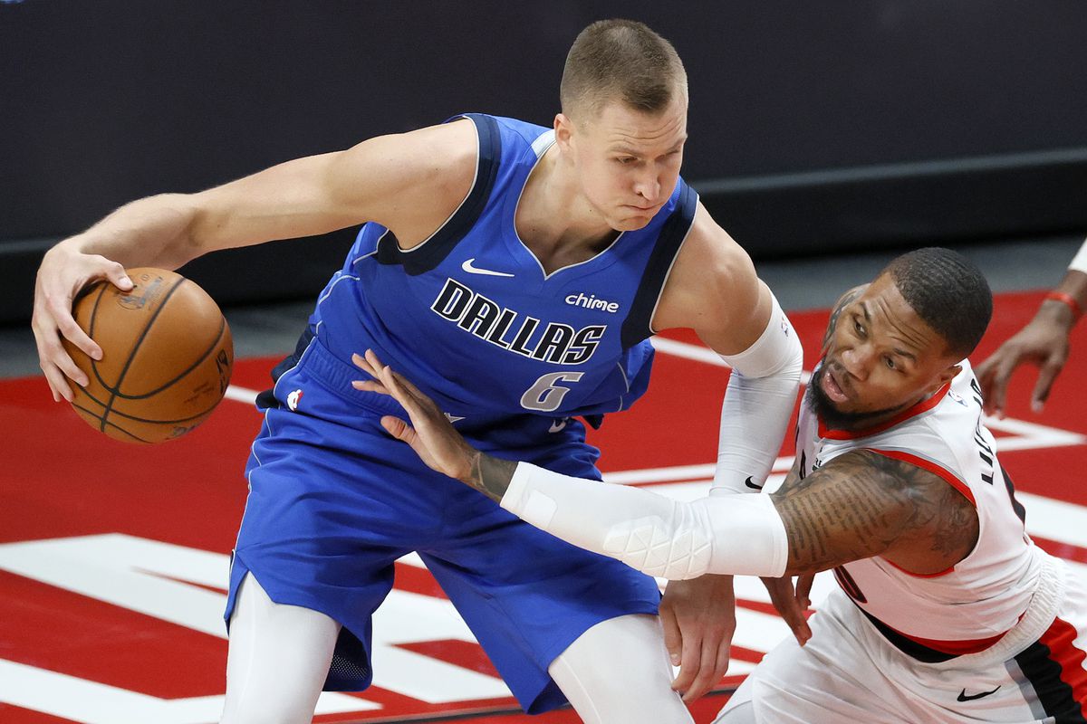 Kristaps Porzingis of the Dallas Mavericks is pressured by Damian Lillard of the Portland Trail Blazers during the third quarter during the third quarter at Moda Center on March 19, 2021 in Portland, Oregon.