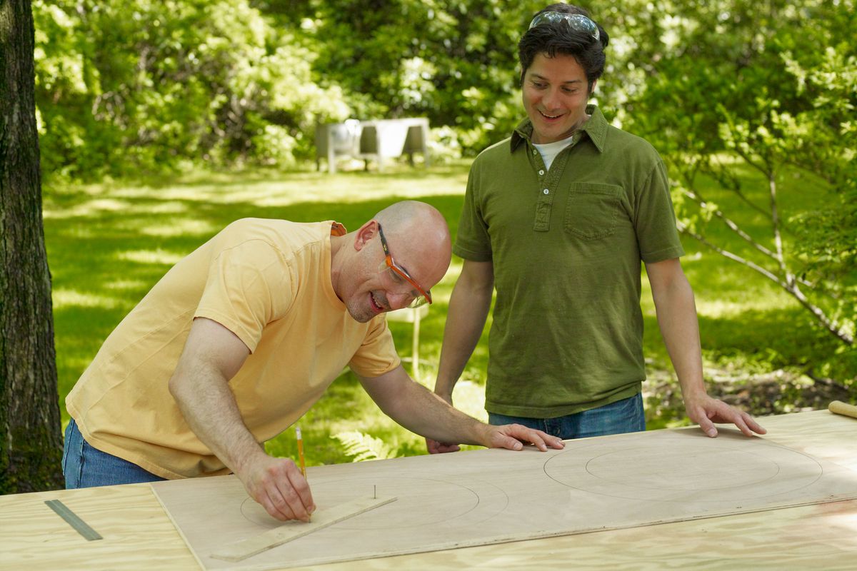 Two men laying creating rings on a board