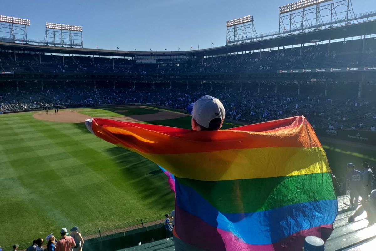 A fan at Wrigley Field drapes a rainbow flag over his back.