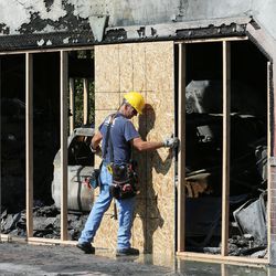 A Utah Disaster Kleenup worker puts up plywood on the doors of a fire-damaged home in West Valley City on Tuesday, Aug. 1, 2017. A newspaper deliveryman got a woman out of the home as it burned.