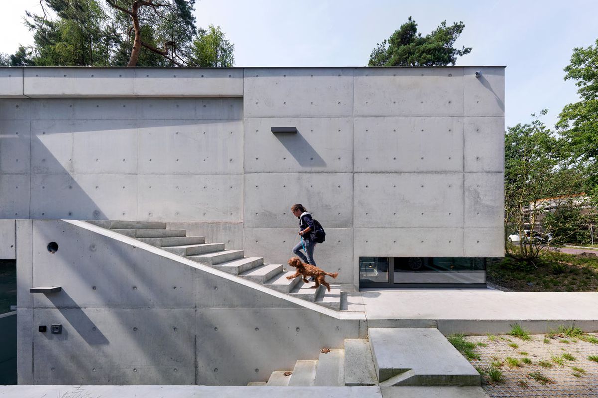 Concrete home with concrete stairs leading to front door