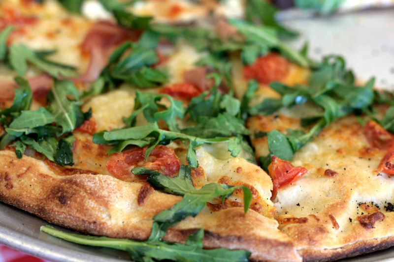 A close-up on a pizza pie topped with arugula and small pepperoni slices