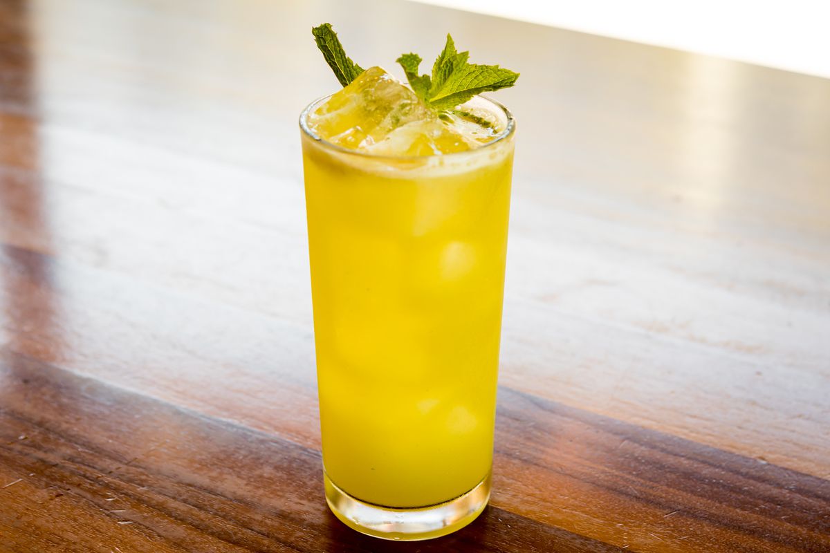 A yellow cocktail in a tall glass.