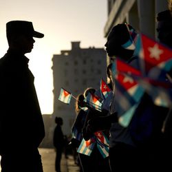 A soldier is silhouetted against the early morning sky as people holding Cuban flags wait for the motorcade transporting the remains of Cuban leader Fidel Castro in Havana, Cuba, Wednesday, Nov. 30, 2016. Castro's ashes have begun a four-day journey across Cuba from Havana to their final resting place in the eastern city of Santiago. 