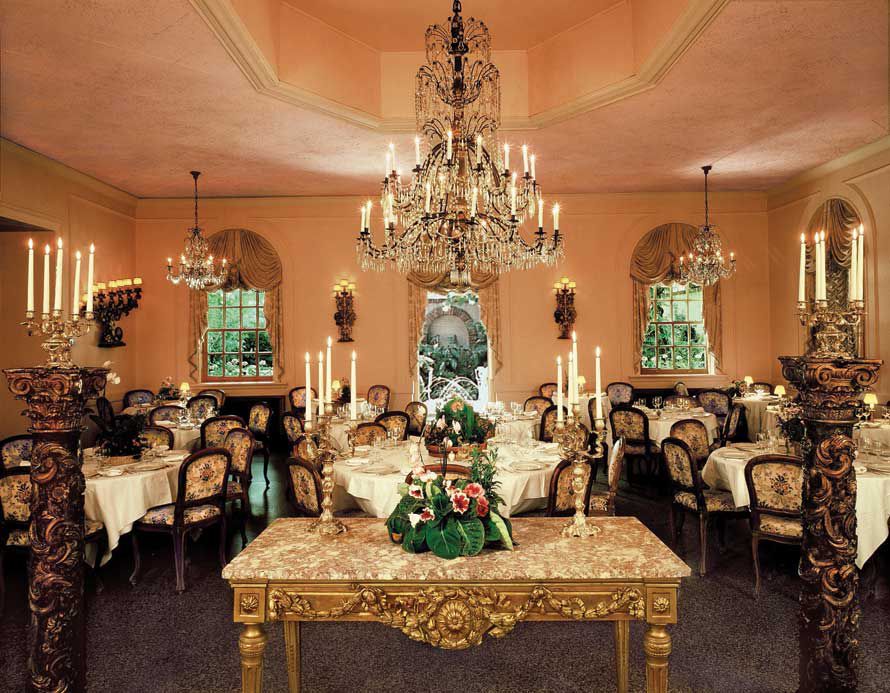 A very ornate rooms with a gilded table and chandeliers.