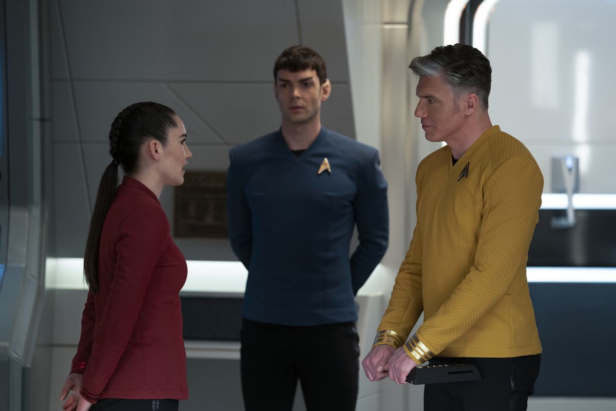 Pike talking to a subordinate while Spock looks on 