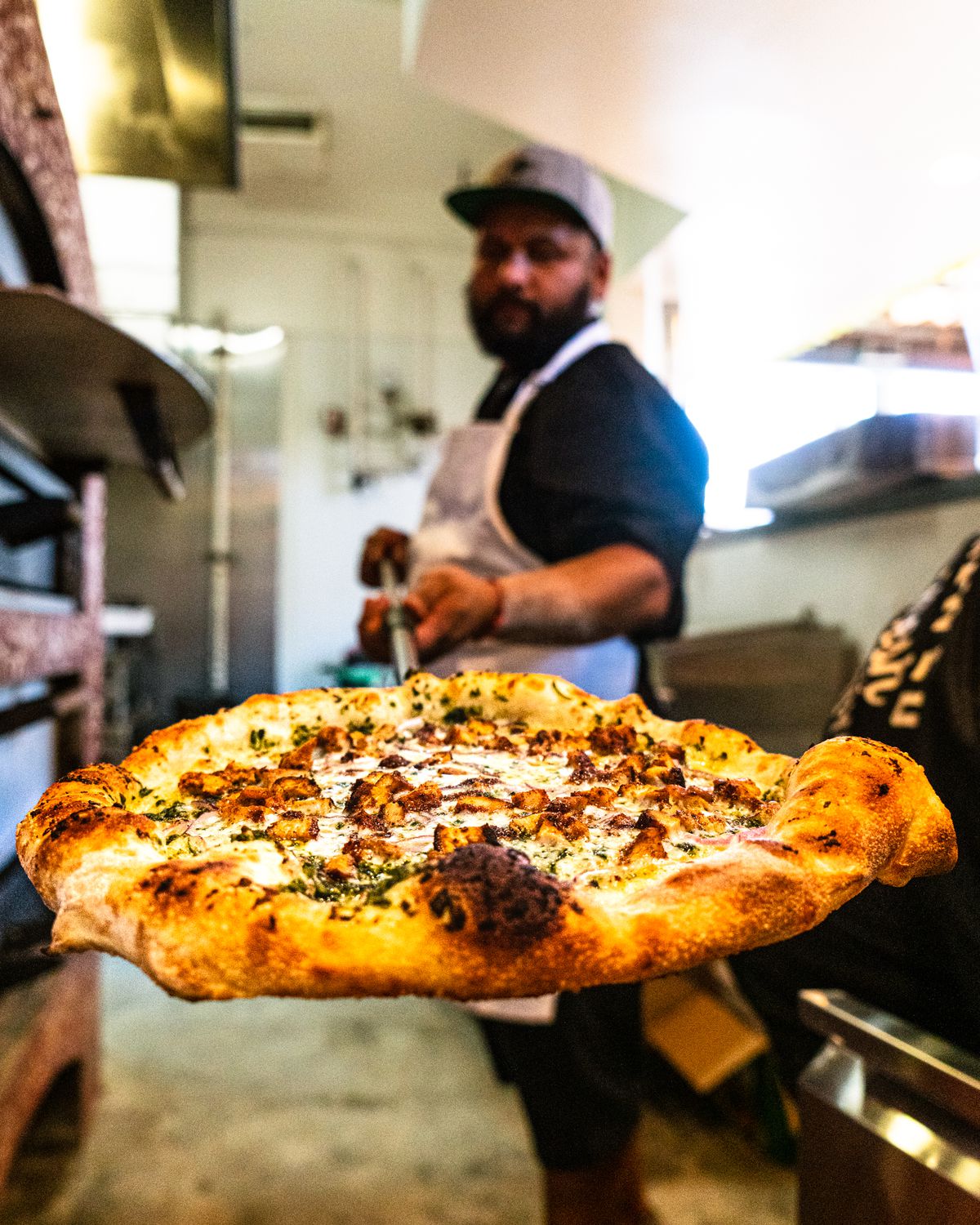 A pizza-maker from MacLeod Ale Brewing Co. holds a freshly made pizza.