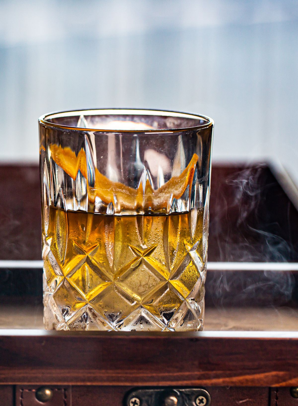 Smoked Honey ‘O made with whiskey, dark rum, orange bitters, and honey syrup presented in a smoke box at Polaris in Atlanta.