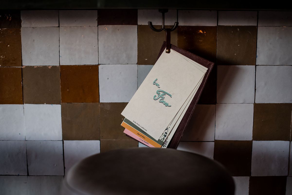 Menu hanging from under the bar counter with white and brown tiles.