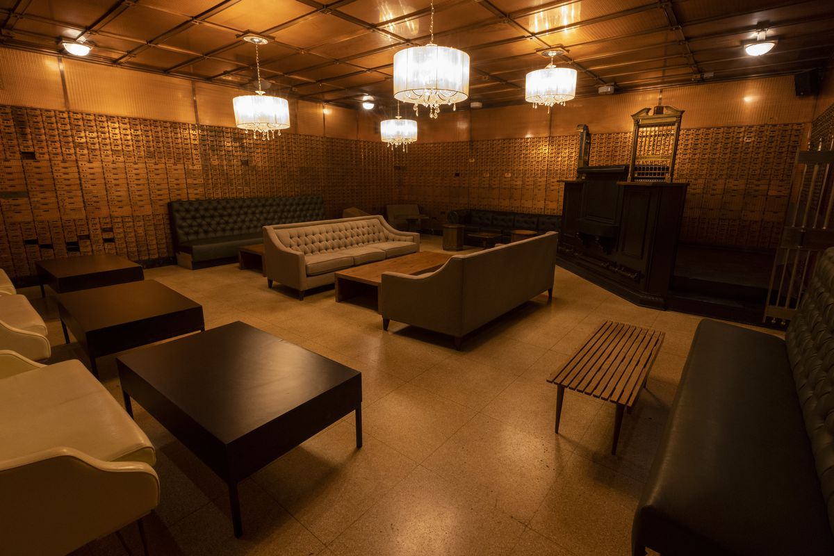 A vintage bank vault filled with couches and tables.