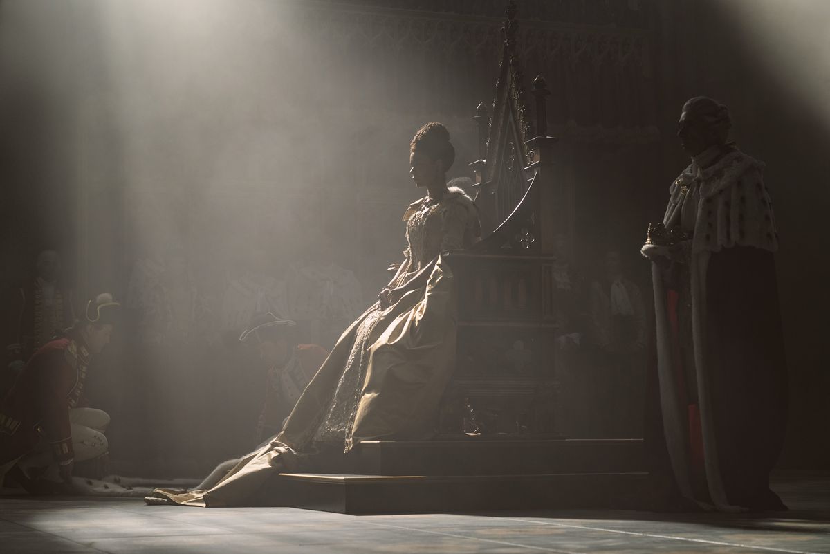 la reina charlotte sentada en su trono, sombras dramáticas que protegen la mayor parte de sus rasgos, con un rayo de sol que la golpea justo en el centro
