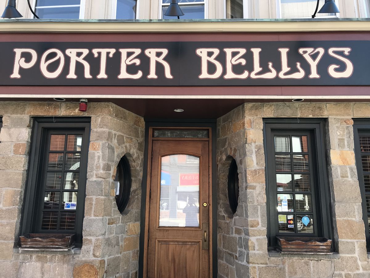 Light brick exterior of a bar with black signage that readers Porter Belly’s in gold on black