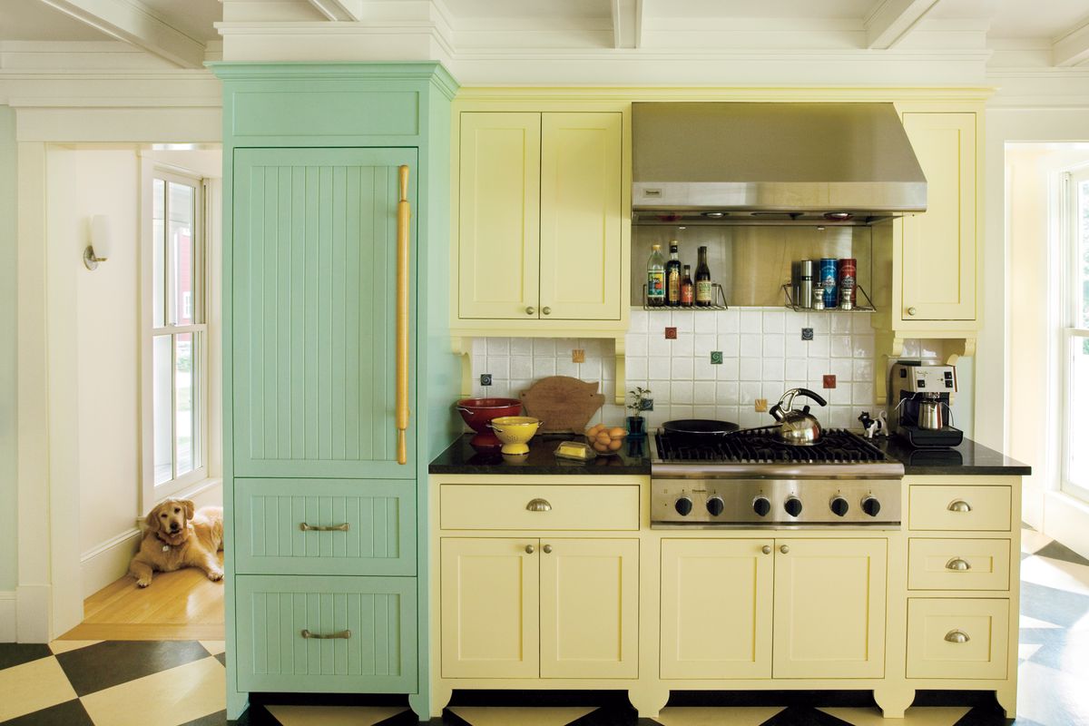 Tall green cupboard next to soft yellow kitchen cabinet and drawers.