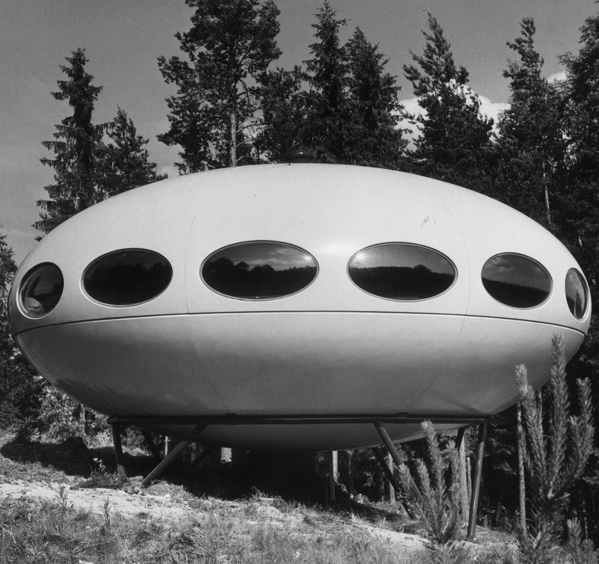 The exterior of a Futuro House. The house is oval shaped with oval windows.