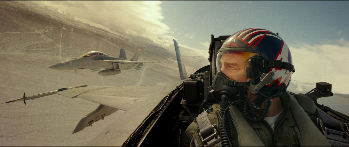 Maverick (Tom Cruise) in the cockpit of a fighter jet, with another flying close by in Top Gun: Maverick