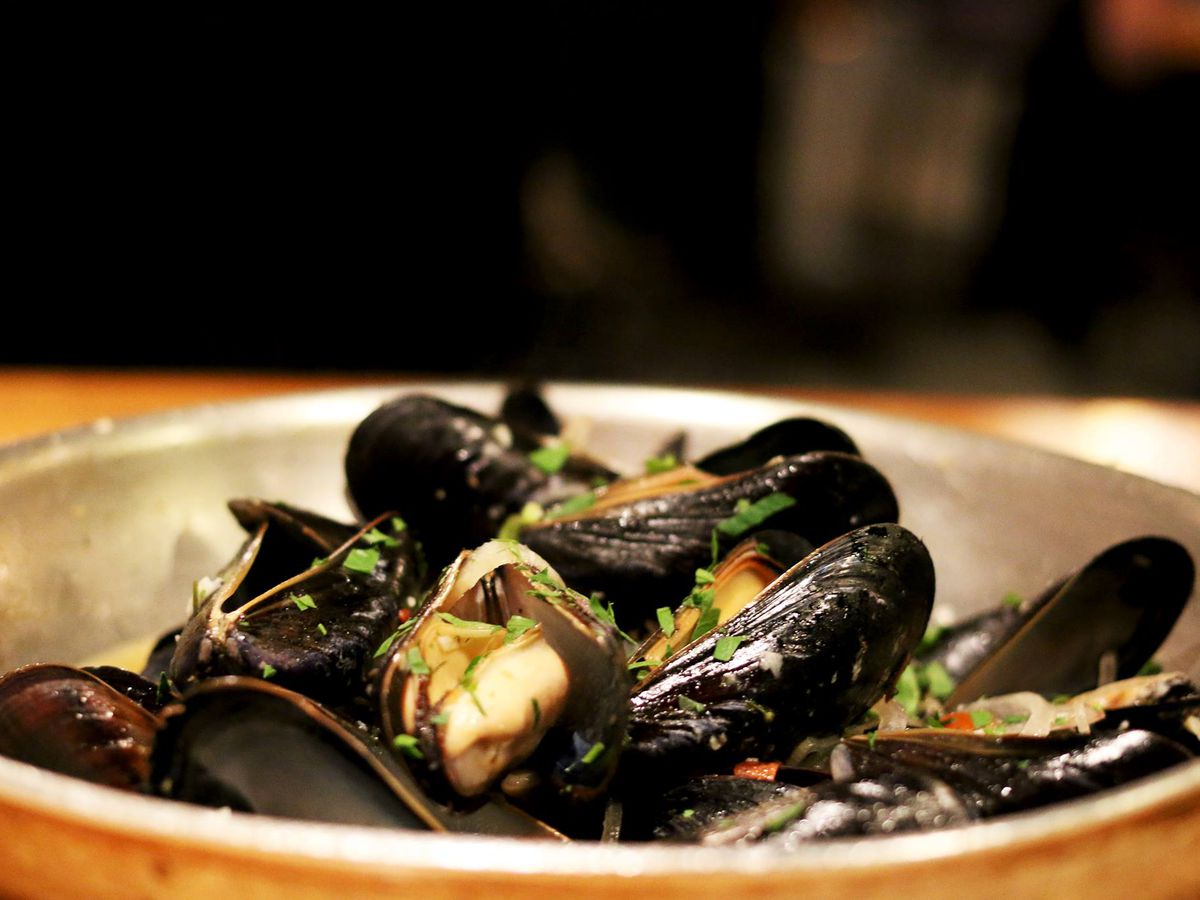 A silver pan is full of steamed mussels