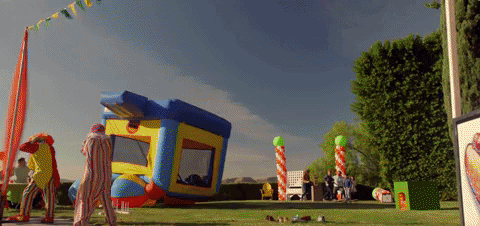 GIF of people surrounding a bouncy castle flying into the air