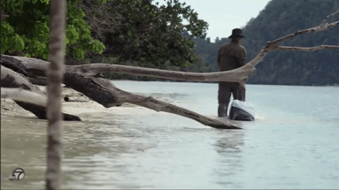 GIF of a man walking away from the camera, rolling a suitcase through the water behind him