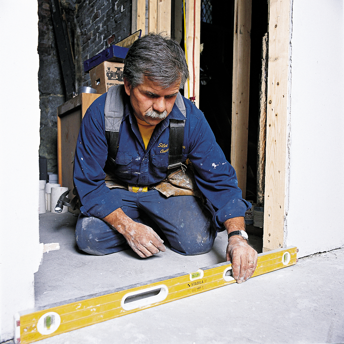 Man Using Level In Doorway To Install Prehung Interior Door
