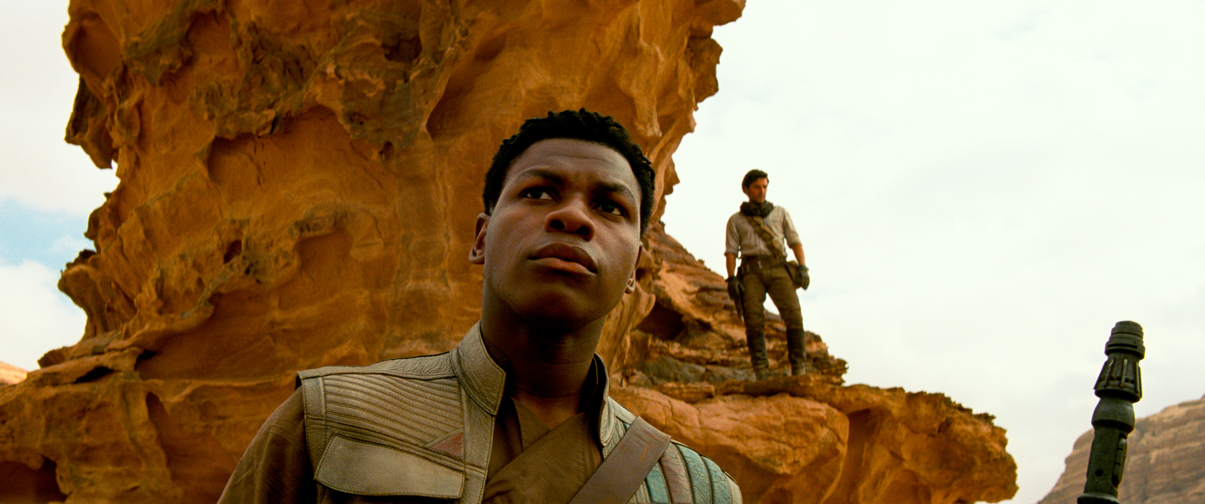 Finn (John Boyega) with Poe (Oscar Isaac) on a ridge behind him in Star Wars: The Rise of Skywalker