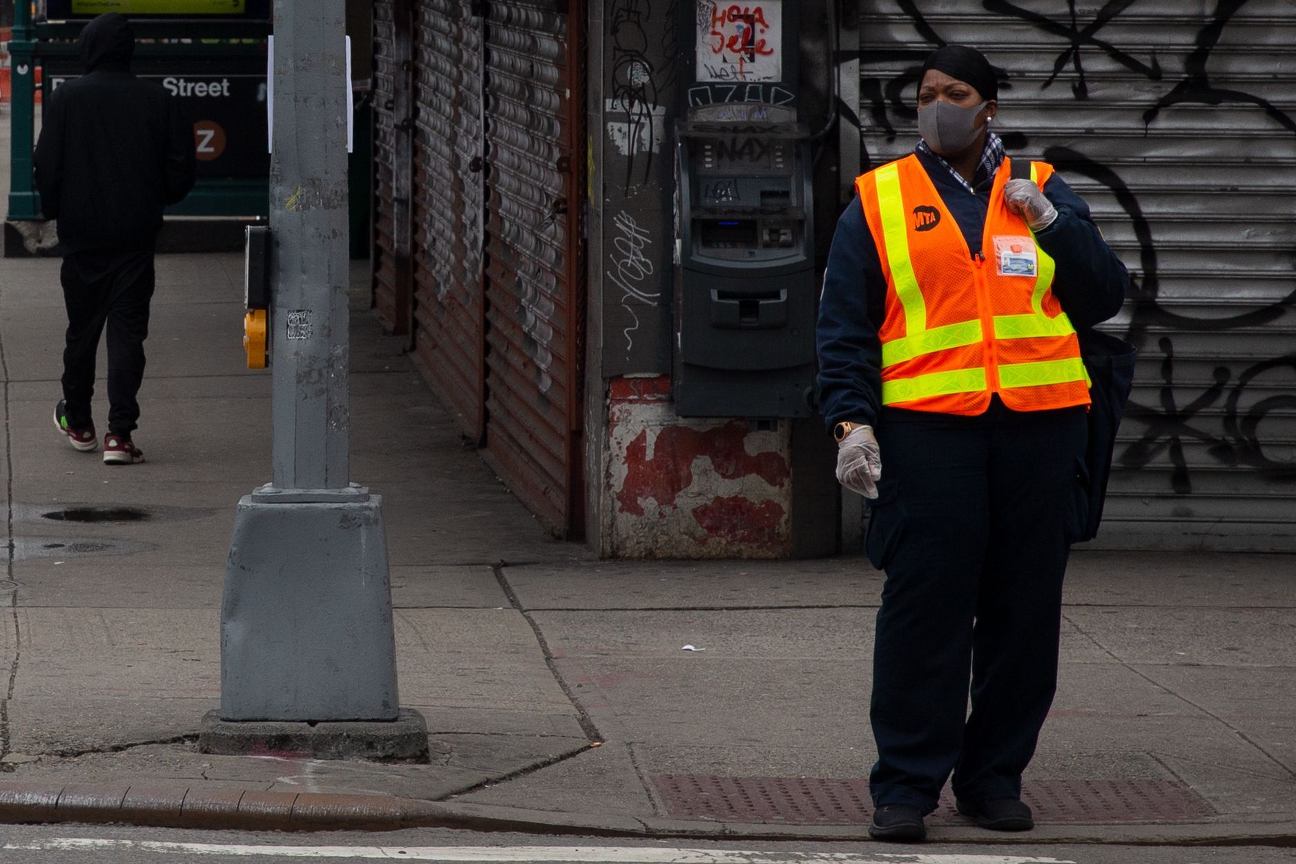 An MTA worker waits to cross Delancey Street during the coronavirus outbreak.