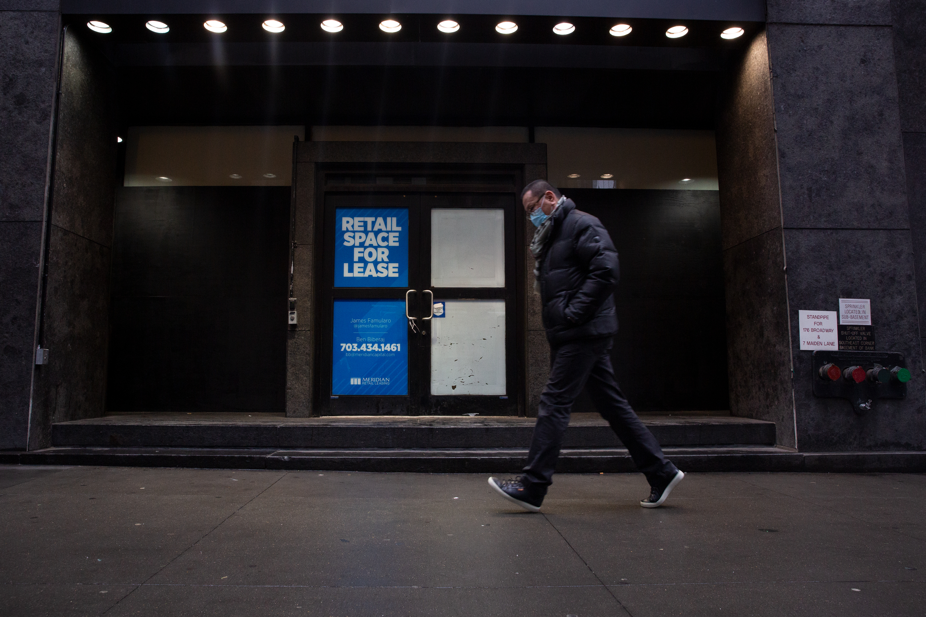 People walk by an empty storefront in Lower Manhattan on Wednesday. 