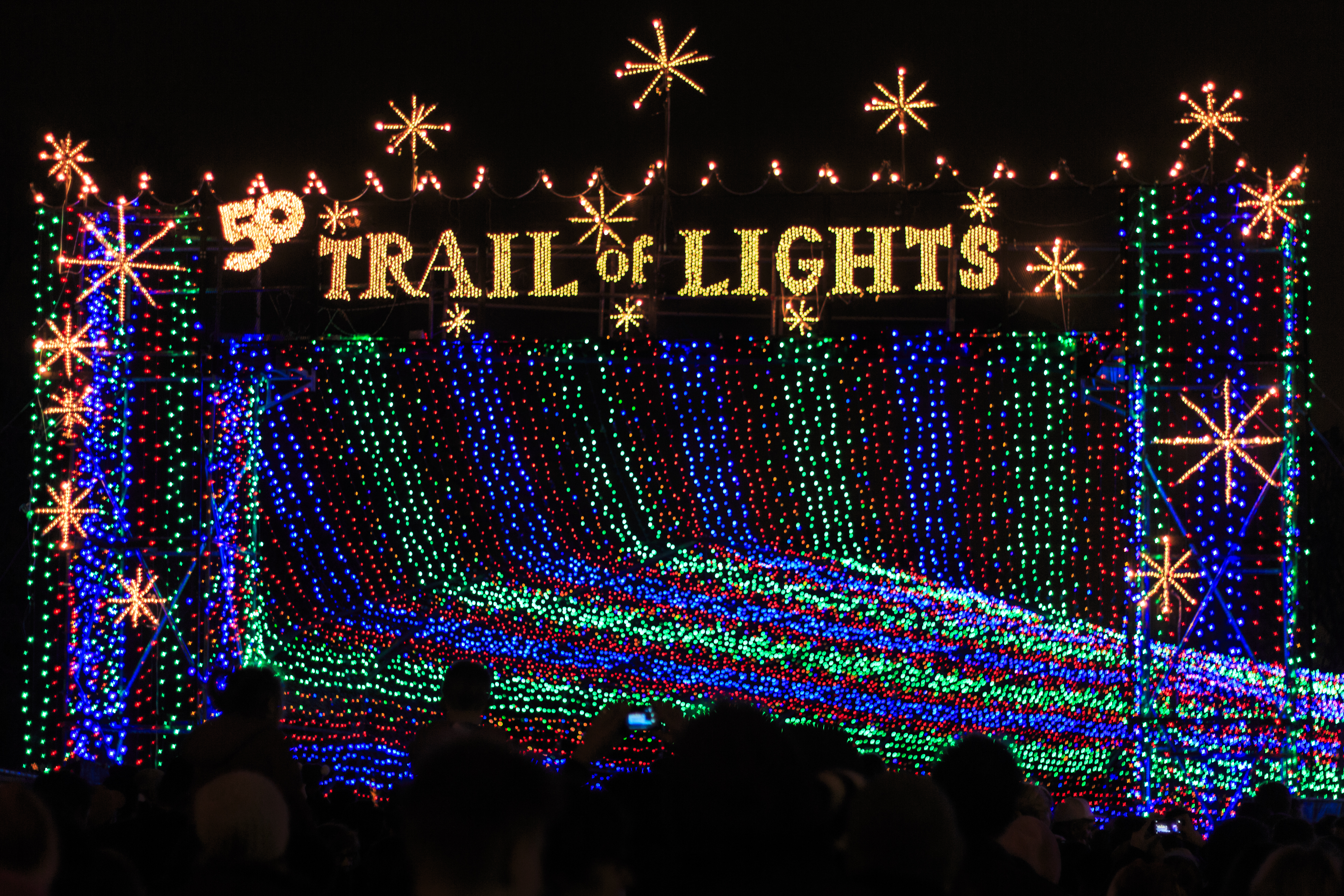 Christmas lights in streams and a lit-up sign reading Trail of Lights.