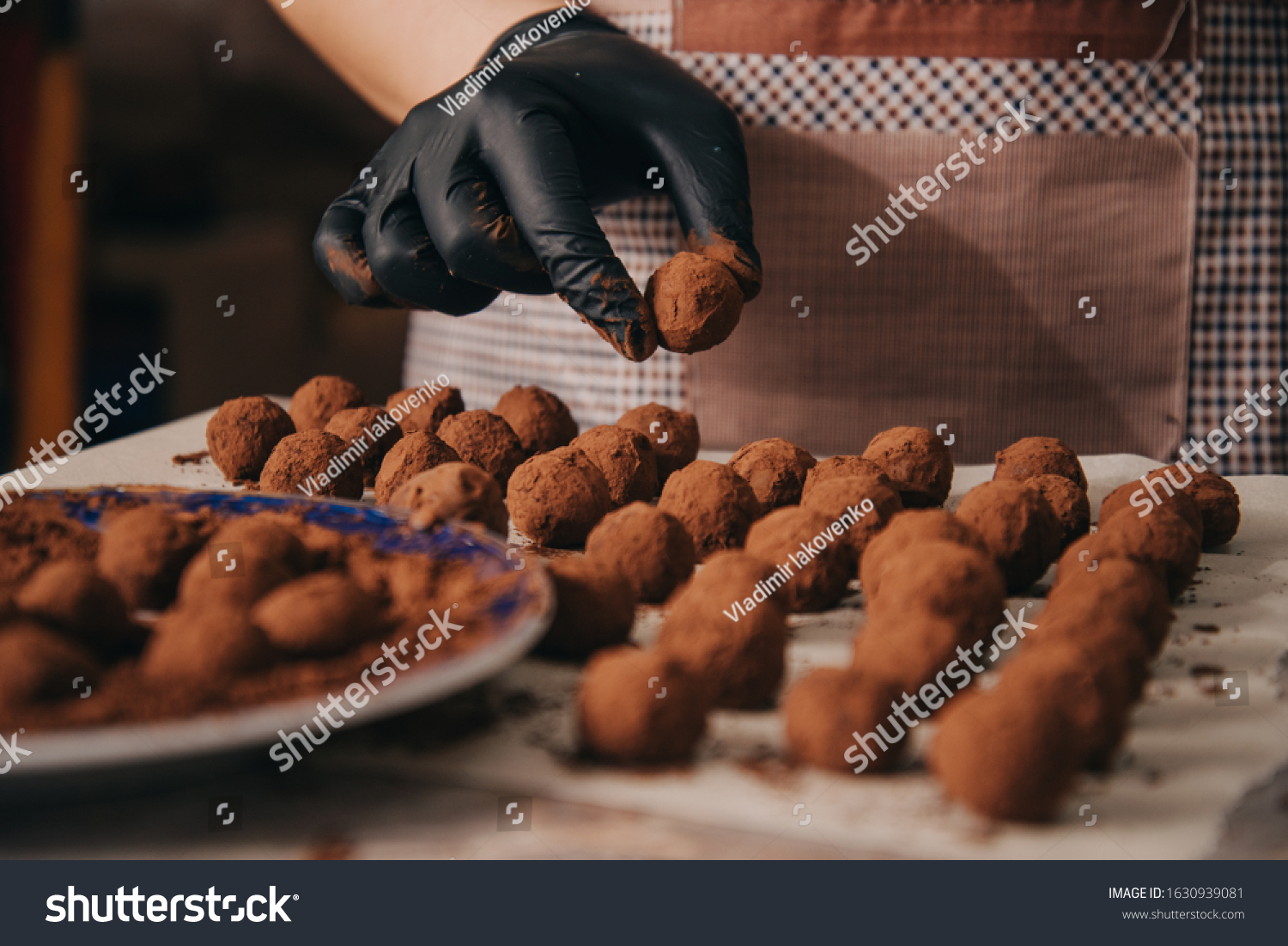 A gloved hand preparing chocolate truffles.