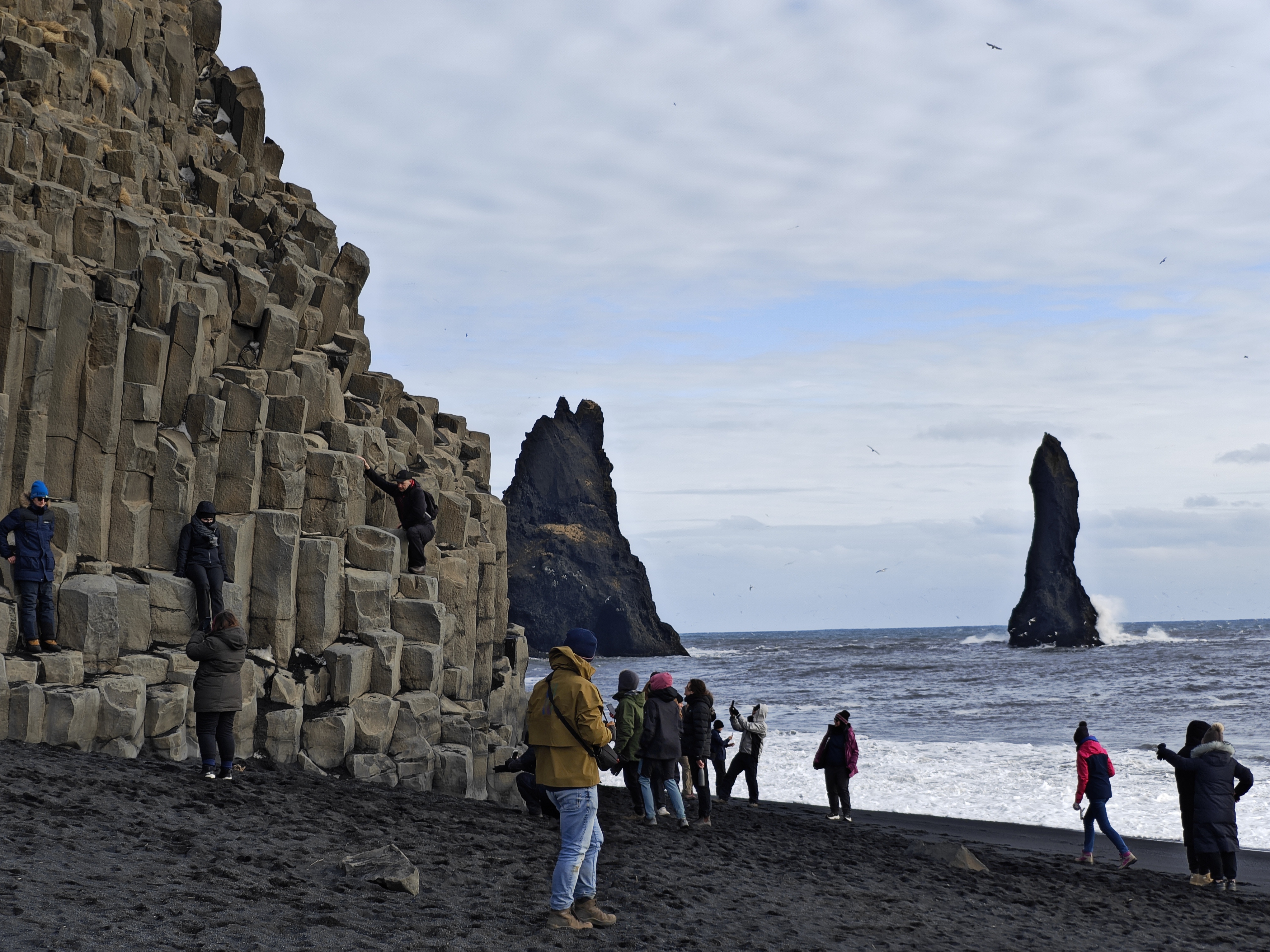 Black sand beach with people in the foreground.